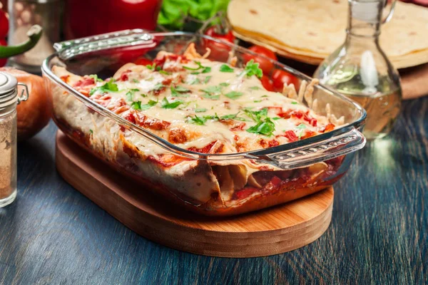 Enchiladas messicani tradizionali con carne di pollo, salsa di pomodoro piccante e formaggio in piatto resistente al calore — Foto Stock