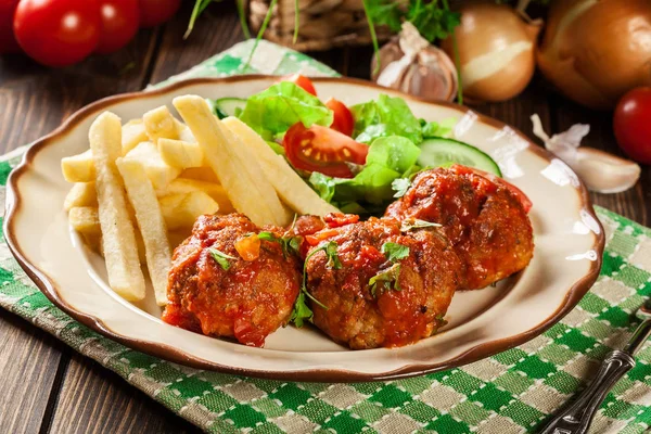 Roasted meatballs in tomato sauce with french fries and salad — Stock Photo, Image