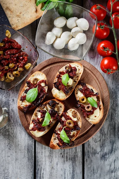 Vorspeise Bruschetta mit sonnengetrockneten Tomaten, Oliven und Mozarel — Stockfoto