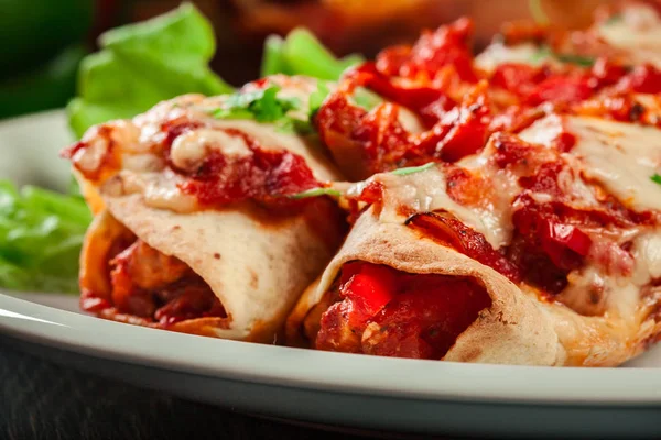 Традиционные мексиканские энчилады с куриным мясом, острым томатным соусом и сыром на тарелке — стоковое фото