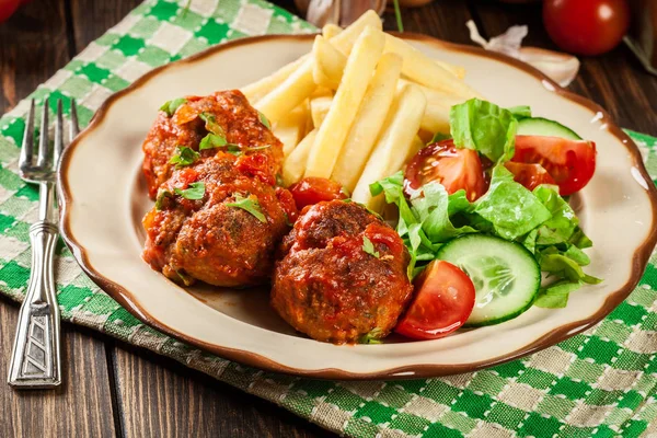 Gebratene Hackbällchen in Tomatensauce mit Pommes und Salat — Stockfoto