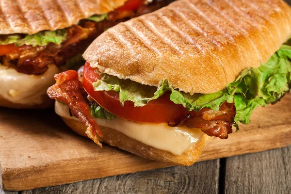 Sandwich de ciabatta tostado con tocino ahumado, queso y tomate —  Fotos de Stock