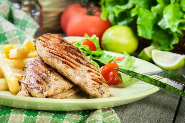 Grilled chicken breasts served with fries — Stock Photo, Image