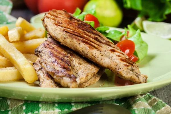 Grilled chicken breasts served with fries — Stock Photo, Image