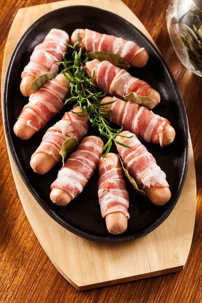 Mini salsichas cruas embrulhadas em bacon defumado — Fotografia de Stock