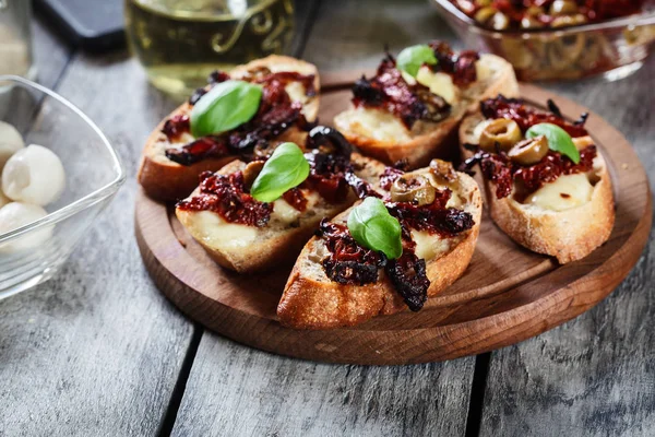 Vorspeise Bruschetta mit sonnengetrockneten Tomaten, Oliven und Mozarella. — Stockfoto