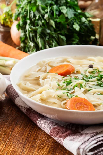 Tasty meat broth with noodles, carror and parsley — Stock Photo, Image