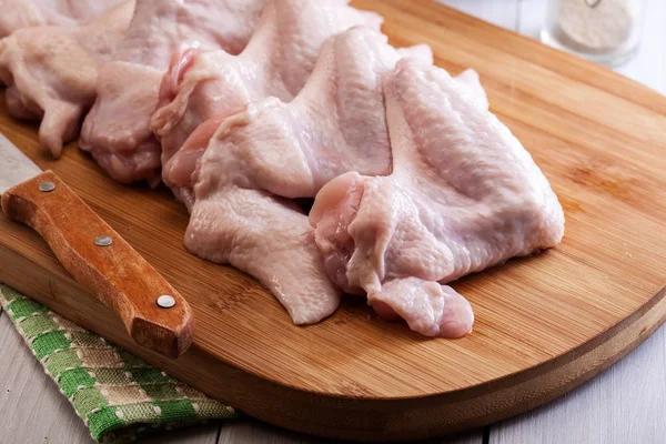 Asas de frango cru na tábua de corte — Fotografia de Stock