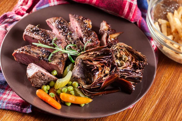 Slices of beef steak served with baked artichoke — Stock Photo, Image