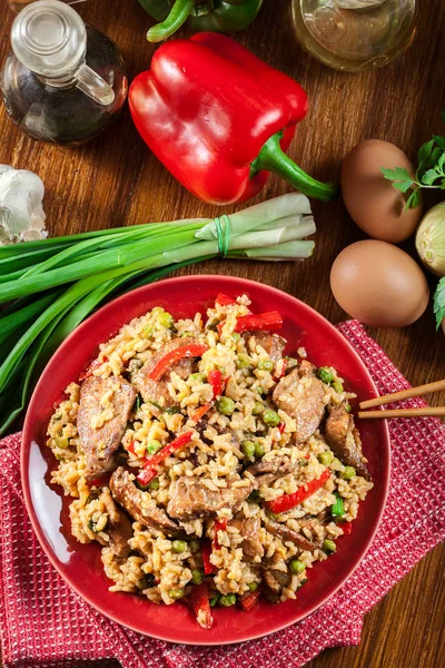 Жареный рис с курицей и овощами на тарелке — стоковое фото