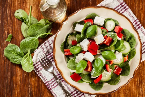 Ensalada de espinacas frescas con feta, pepino y pimentón rojo en un pla —  Fotos de Stock