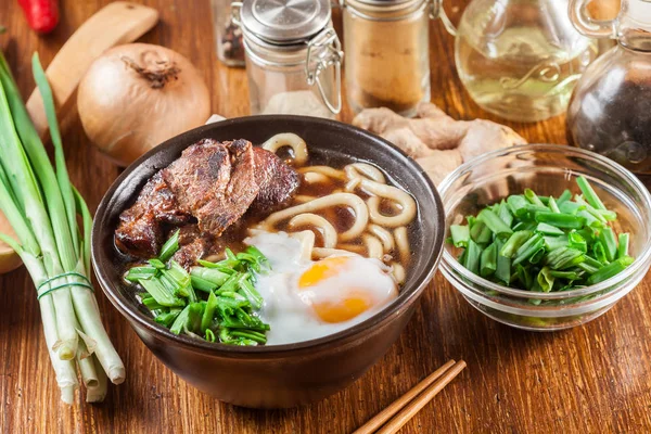 Японская лапша Удон с говядиной, яйцом, зеленым луком и супом — стоковое фото
