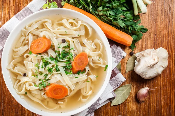 Tasty meat broth with noodles, carror and parsley — Stock Photo, Image