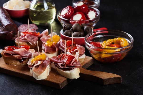Spanish tapas with slices jamon serrano and grilled pepper. Also olives, salami, pickled onions, and peppers stuffed with cheese — Stock Photo, Image