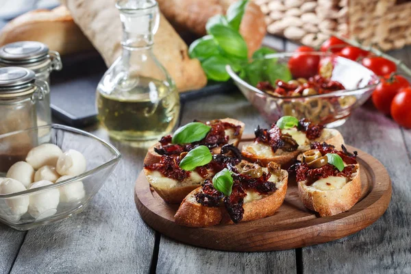 Předkrm bruschetta se sušenými rajčaty, olivami a mozarella. — Stock fotografie