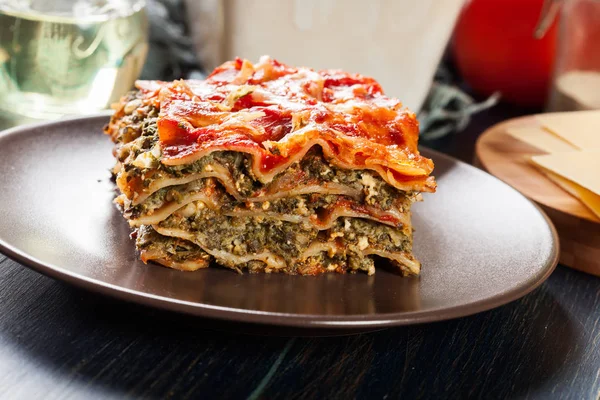 Pezzo di gustose lasagne calde con spinaci su un piatto — Foto Stock