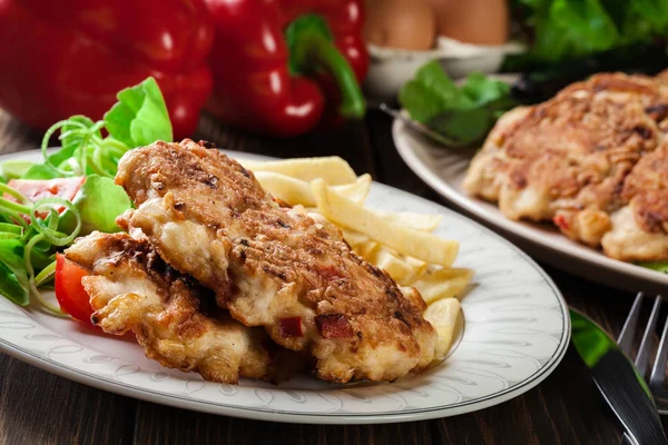 Chicken medallions with red peppers served with chips — Stock Photo, Image
