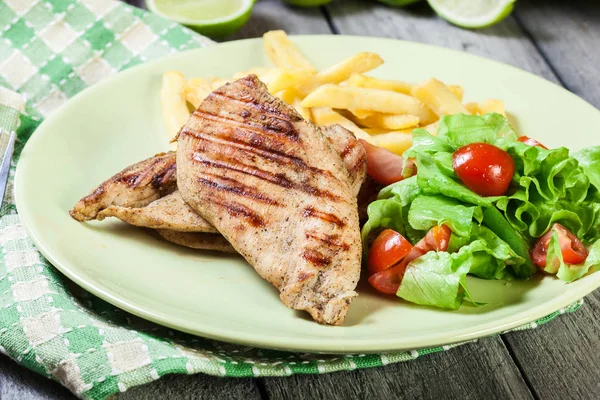 Grilled chicken breasts served with fries — Stock Photo, Image