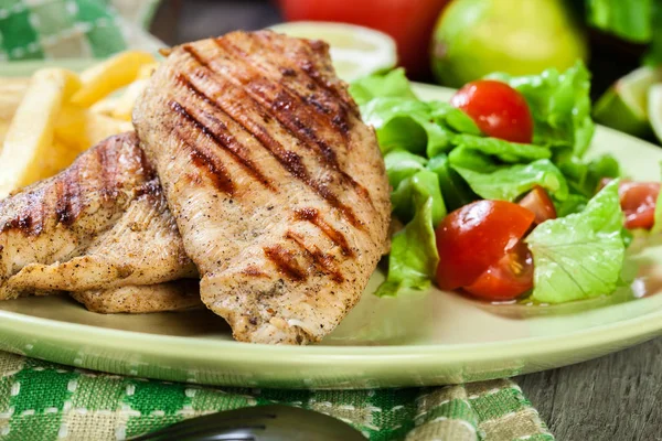Grilled chicken breasts served with fries — Stock Photo, Image