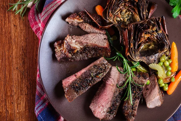 Slices of beef steak served with baked artichoke — Stock Photo, Image