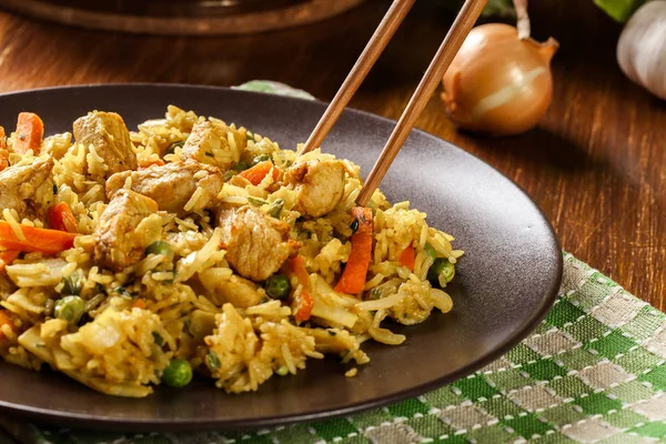 Жареный рис наси горенг с курицей и овощами на тарелке — стоковое фото