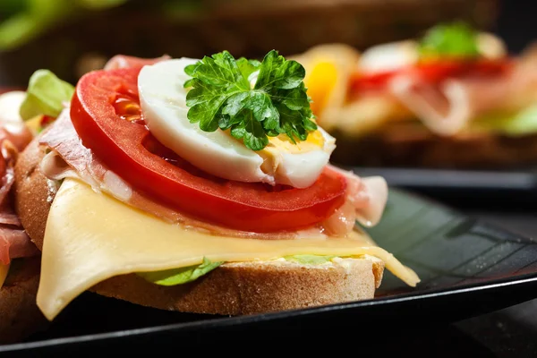 Delicioso sándwich con jamón de jamón, queso, tomate y huevo — Foto de Stock