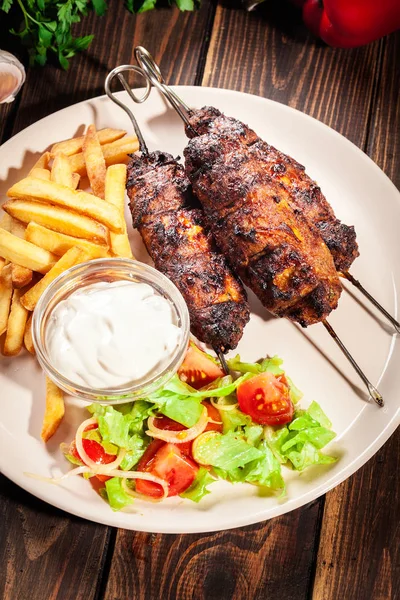 Shish kebab grigliato servito con patatine fritte e insalata — Foto Stock