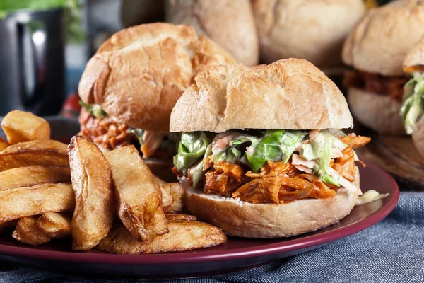 Pulled chicken sandwich with salad and bbq sauce served with french fries