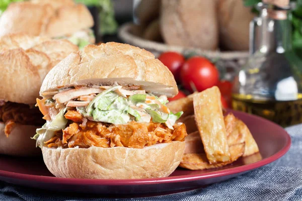 Pulled chicken sandwich with salad and bbq sauce served with french fries