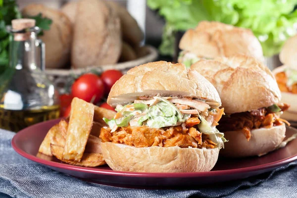 Pulled chicken sandwich with salad and bbq sauce served with french fries