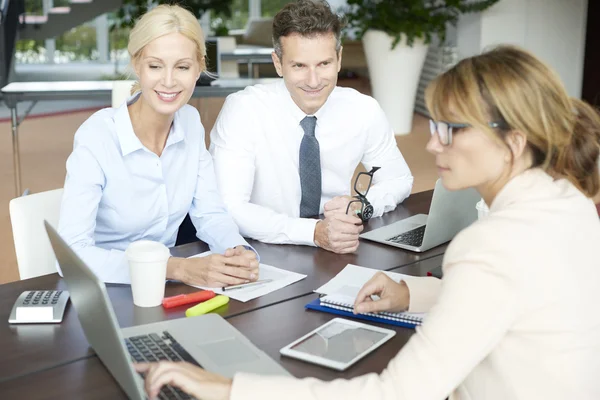 Agent sitting at office with her clients — стоковое фото