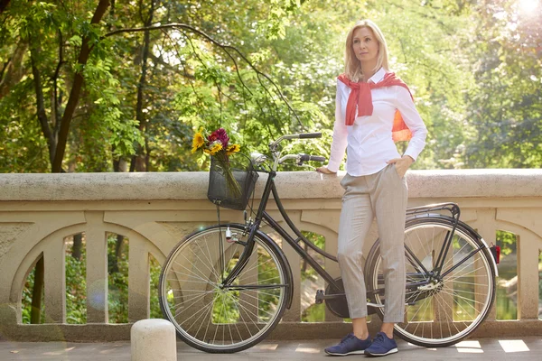 Donna in piedi con la sua bicicletta — Foto Stock