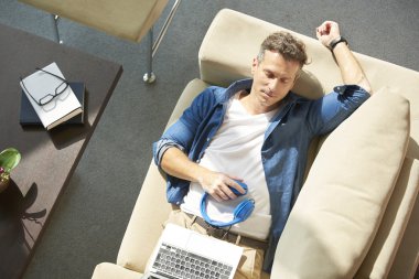 Dizüstü bilgisayar ile kanepede rahat adam 