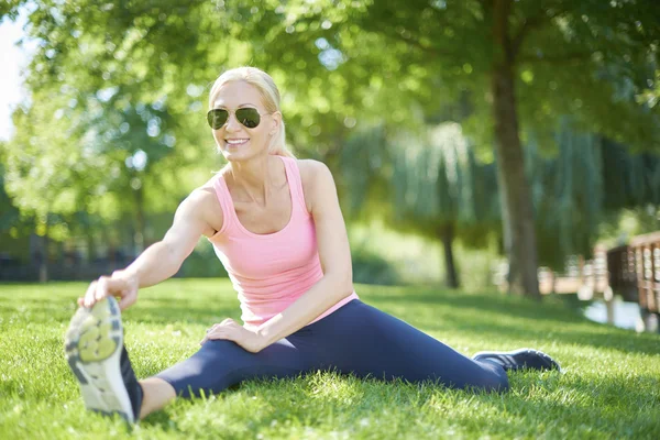 Woman sitting in the grass and stretching — Stock Photo, Image
