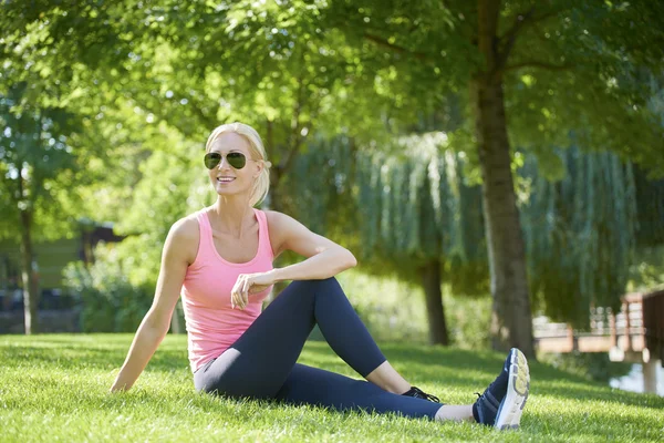 Woman sitting in grass and stretching — Stock Photo, Image
