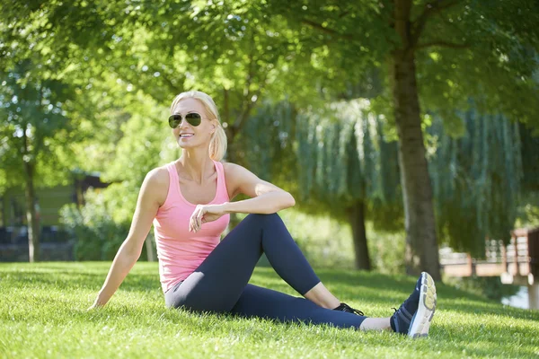 Woman sitting in grass and stretching — Stock Photo, Image