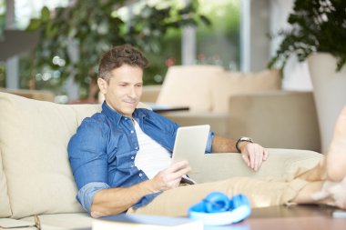  onun tableti kullanan gülümseyen casual adam