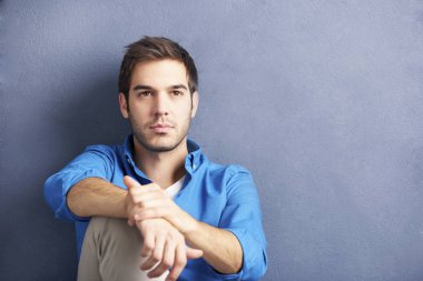 Duvar tarafından oturan genç adam.