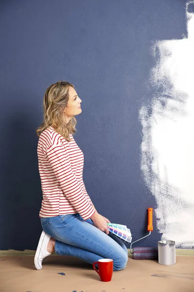 Donna pittura parete a casa. — Foto Stock
