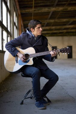 Adam akustik gitar çalıyor. 