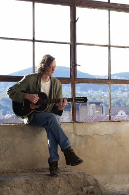 Genç adam akustik gitar çalıyor. 