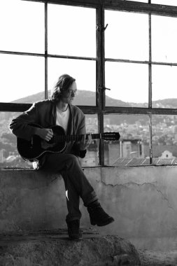 Genç adam akustik gitar çalıyor. 