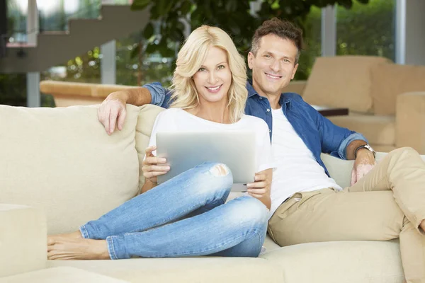 Couple assis avec un ordinateur portable à la maison — Photo