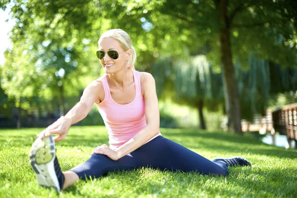 Young woman sitting and stretching — Stock Photo, Image