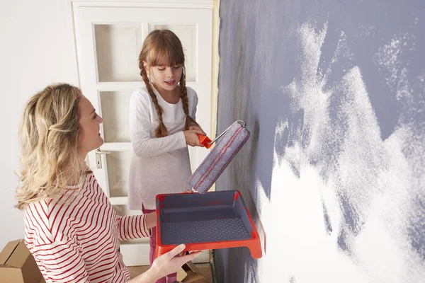 Dochter schilderen muur terwijl haar moeder — Stockfoto