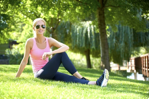 Mulher sentada no parque e alongamento — Fotografia de Stock