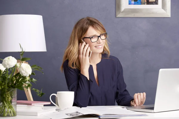 Бізнес-леді робить дзвінок і використовує ноутбук — стокове фото