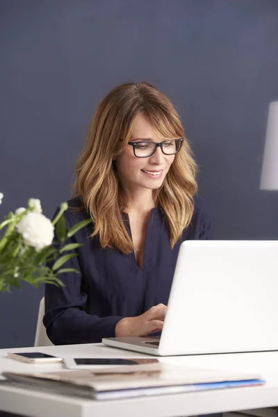Smiling female typing on laptop — Stock Photo, Image
