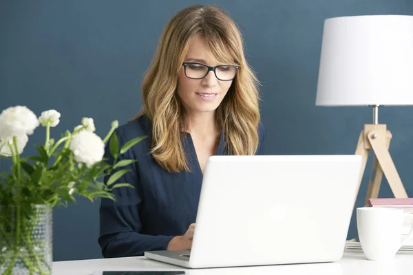 Mulher usando seu laptop enquanto trabalhava — Fotografia de Stock