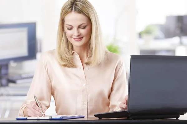 Empresária sentada na frente de um laptop — Fotografia de Stock